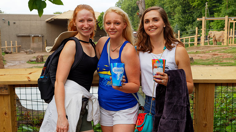 Three guests enjoying ZooBrew in front of the elephant habitat